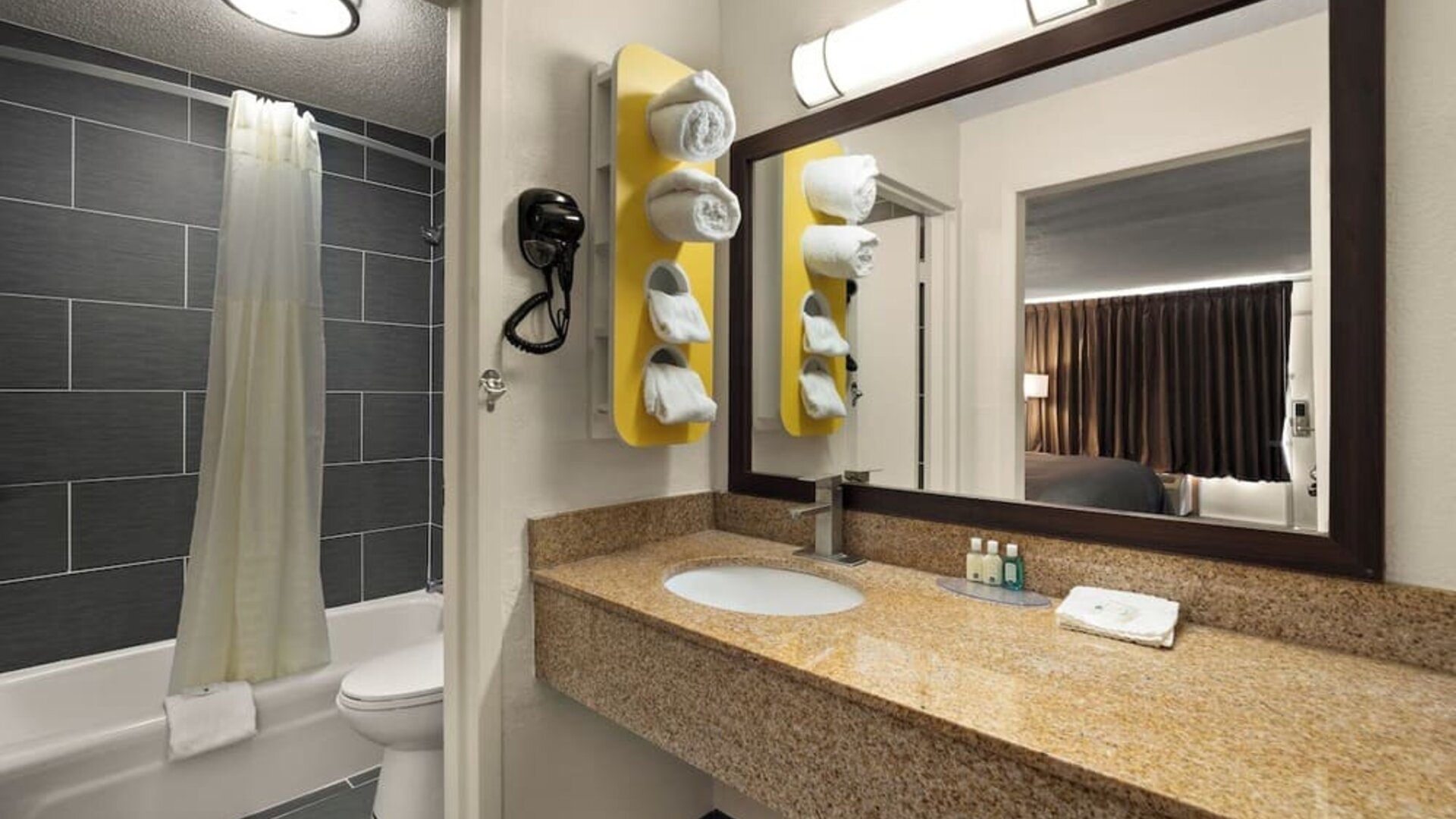 Bathroom with granite vanity, bathtub and shower combination, large mirror and open sink area at Quality Inn Yemassee - Point South I-95.