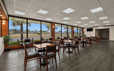 Bright breakfast dining area with wooden tables, large windows and views of the hotel grounds at Quality Inn Yemassee - Point South I-95.