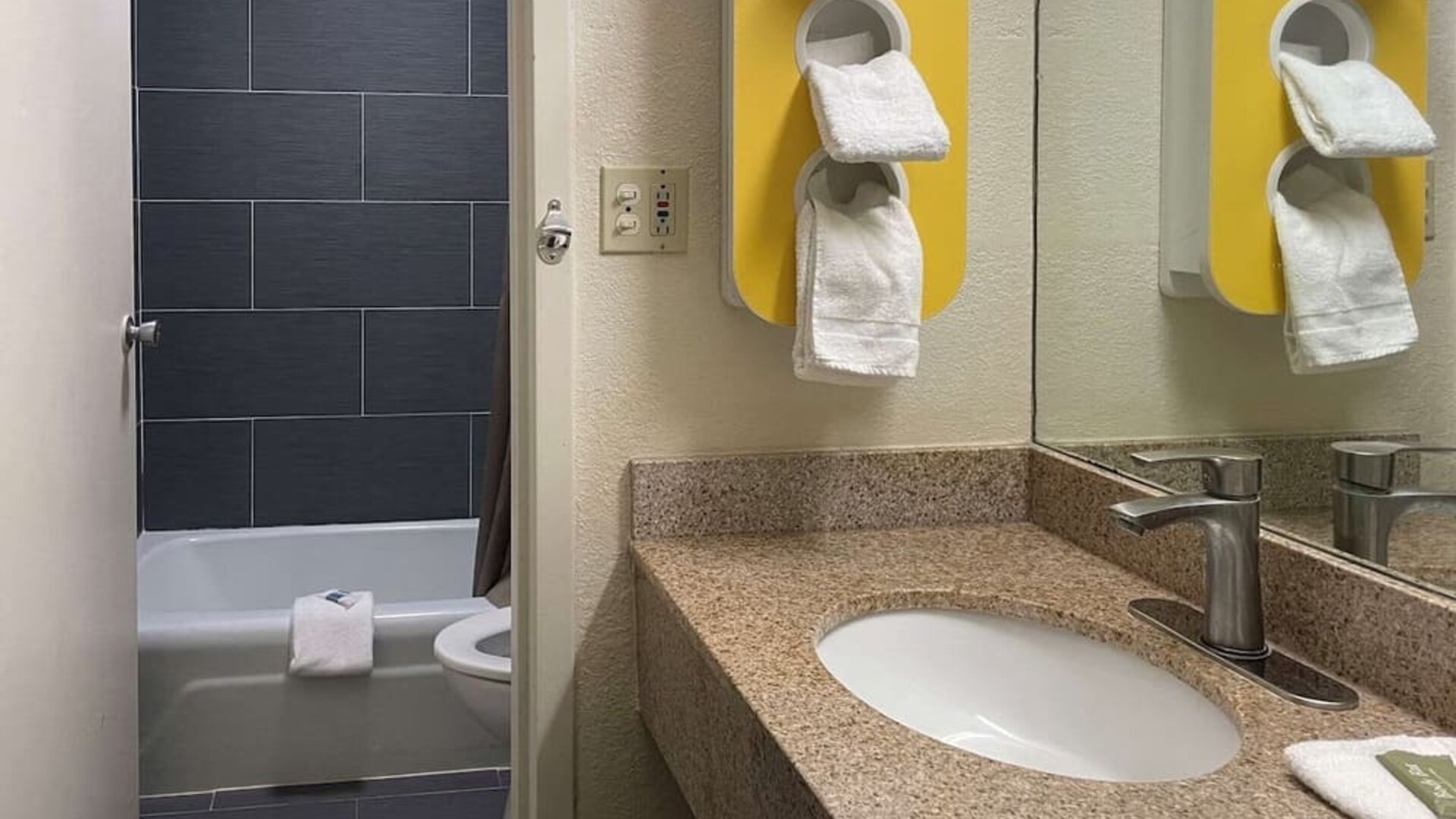Bathroom with granite vanity, bathtub and shower combination, towel storage and modern fixtures at Econo Lodge Yemassee.