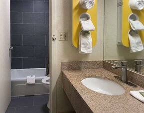 Bathroom with granite vanity, bathtub and shower combination, towel storage and modern fixtures at Econo Lodge Yemassee.