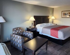 King guest room with seating area, coffee table and bedside lamps beside the bed at Econo Lodge Yemassee.