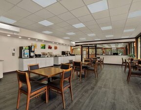 Breakfast dining area with wooden tables, buffet station and large windows overlooking the grounds at Econo Lodge Yemassee.