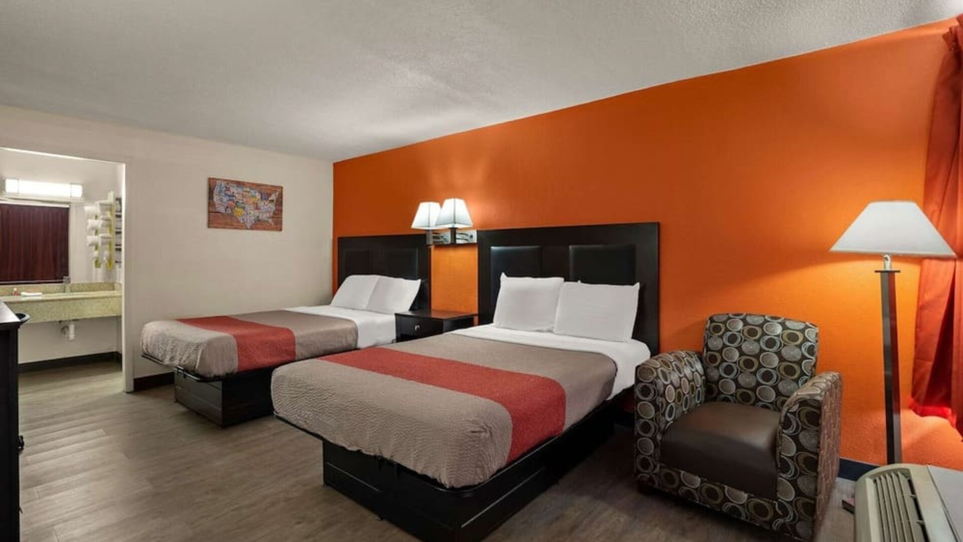 Guest room with two double beds, accent wall, armchair and open vanity area at Econo Lodge Yemassee.