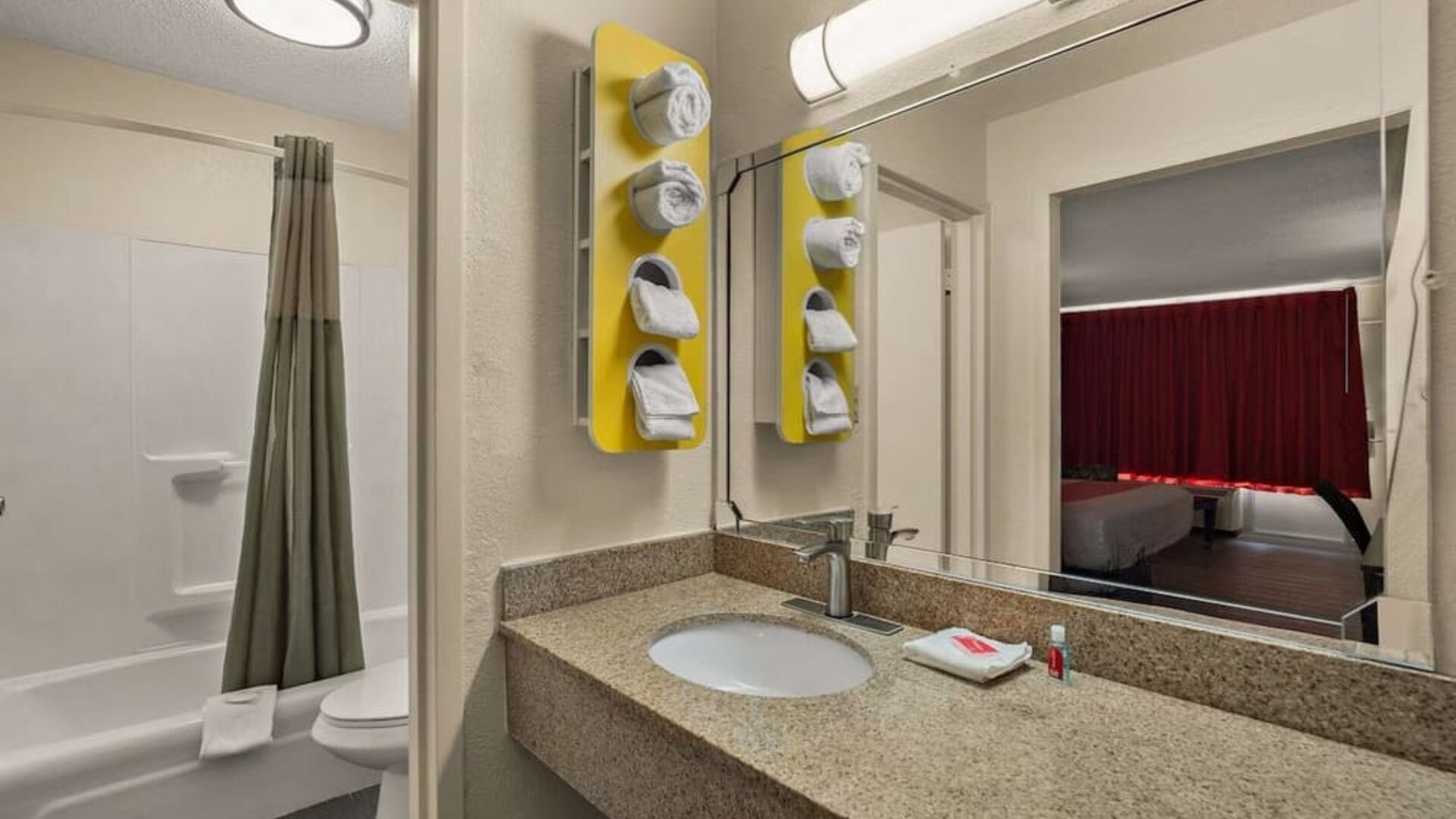 Bathroom with granite vanity, bathtub and shower combination reflected in a large mirror at Econo Lodge Yemassee.