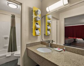 Bathroom with granite vanity, bathtub and shower combination reflected in a large mirror at Econo Lodge Yemassee.