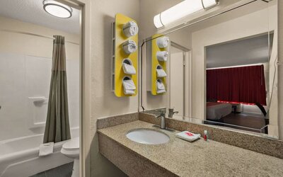 Bathroom with granite vanity, bathtub and shower combination reflected in a large mirror at Econo Lodge Yemassee.
