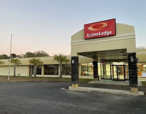 Hotel entrance with covered porte cochère, illuminated Econo Lodge sign and palm trees at Econo Lodge Yemassee.