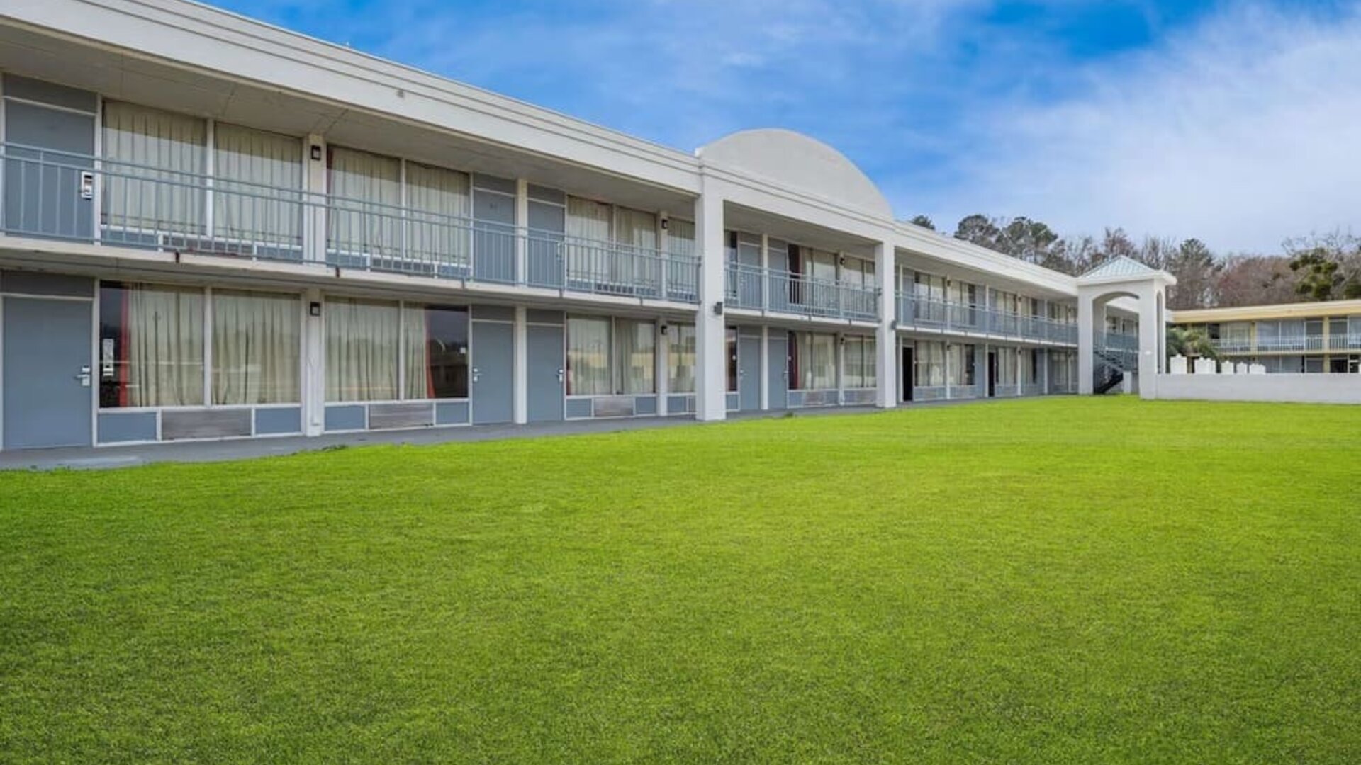 Two-story hotel exterior overlooking a spacious grassy courtyard with guest room balconies at Econo Lodge Yemassee.
