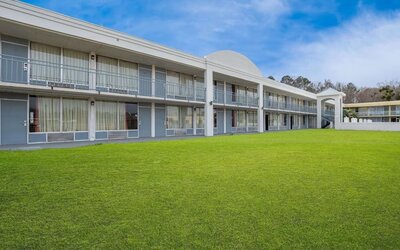 Two-story hotel exterior overlooking a spacious grassy courtyard with guest room balconies at Econo Lodge Yemassee.