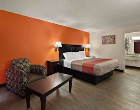 Spacious king guest room with armchair, coffee table and open vanity area at Econo Lodge Yemassee.