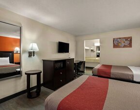 Guest room with two double beds, wall-mounted TV, microwave and workspace at Econo Lodge Yemassee.