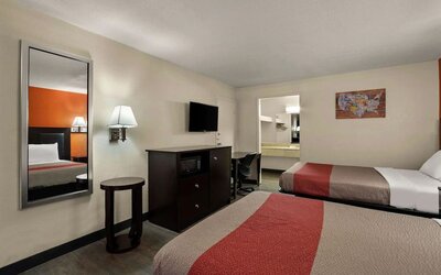 Guest room with two double beds, wall-mounted TV, microwave and workspace at Econo Lodge Yemassee.