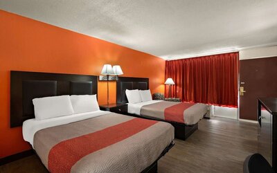 Guest room with two double beds, orange accent wall and exterior entry door at Econo Lodge Yemassee.