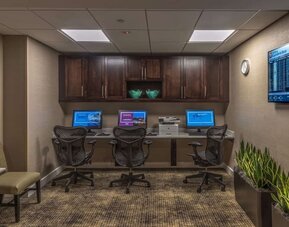 Business center with three desktop computers, printer, ergonomic chairs, and workspace for guests needing to stay productive.