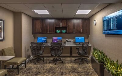 Business center with three desktop computers, printer, ergonomic chairs, and workspace for guests needing to stay productive.