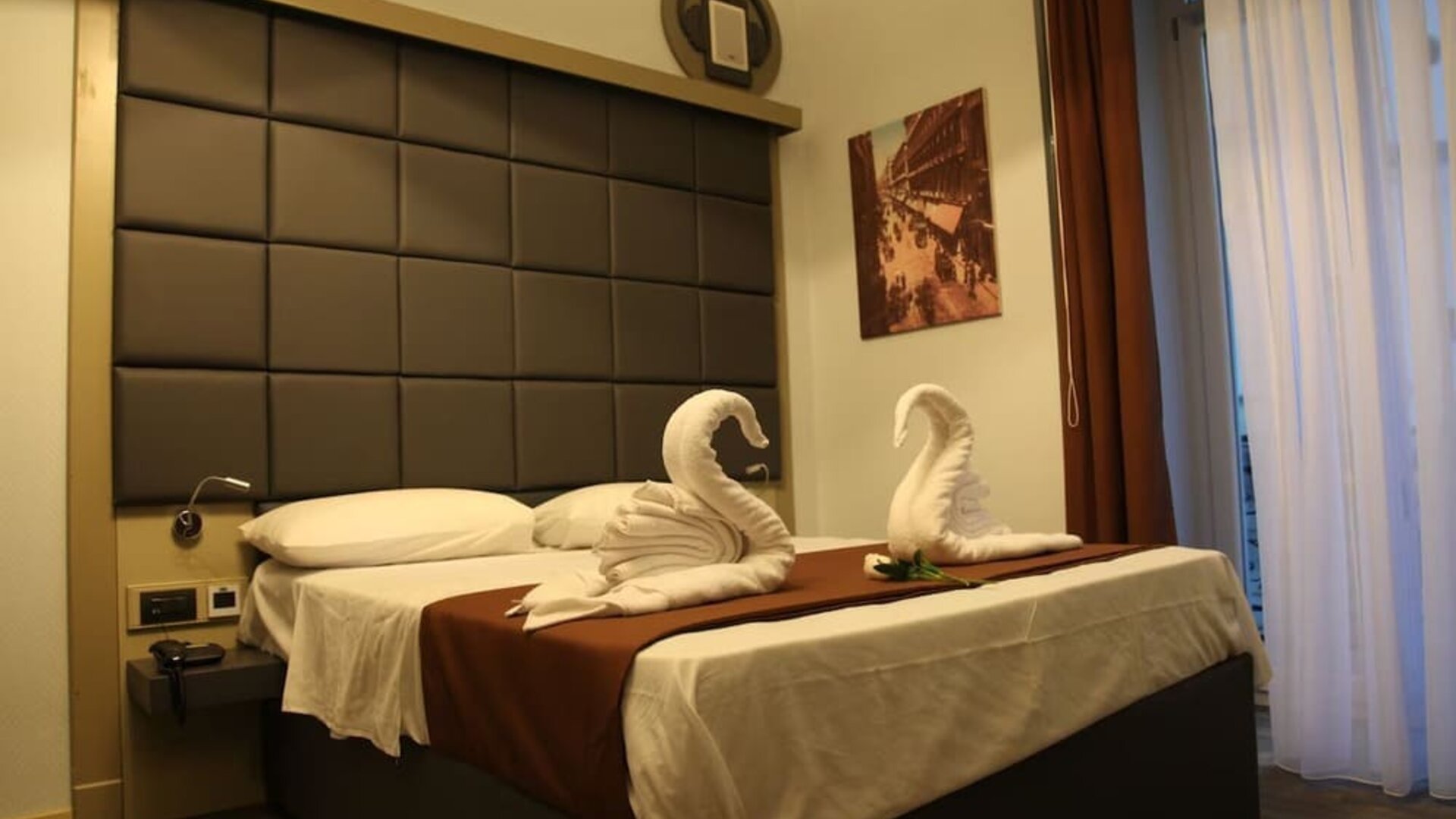 Cozy double guest room with plush bedding, decorative towel swans and natural light at Dolce Vita Rooms & Breakfast.