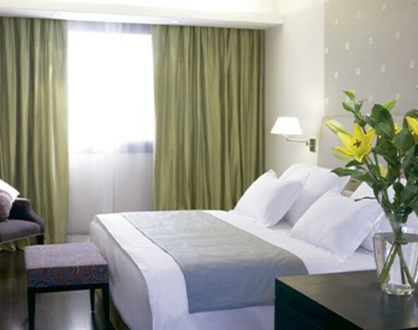 Spacious guest room with king bed, seating area, work space and large window at NH Buenos Aires 9 De Julio.