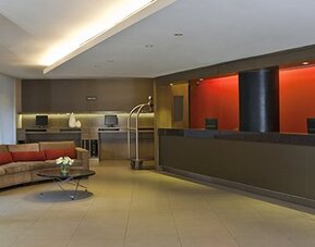 Contemporary hotel reception with front desk, revolving entrance and welcoming lobby seating at NH Buenos Aires 9 De Julio.