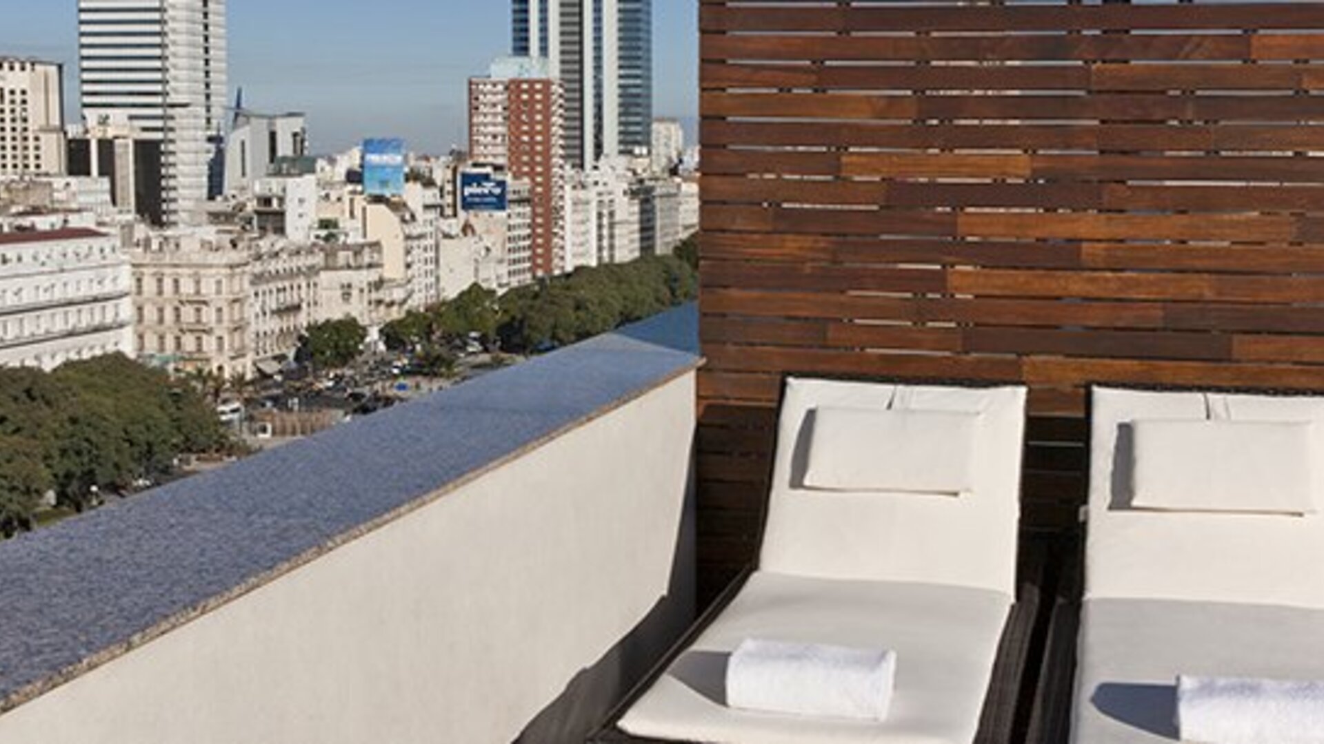 Rooftop sun terrace with comfortable loungers and panoramic city skyline views at NH Buenos Aires 9 De Julio.