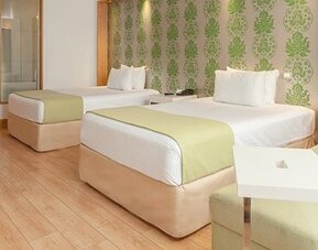 Contemporary guest room with two double beds, sofa seating and modern amenities at NH Collection Mexico City Airport T2.
