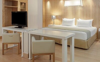 Studio-style suite with king bed, dining table, work area and spacious open-plan layout at NH Collection Mexico City Airport T2.