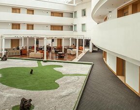 Bright interior courtyard with open atrium, landscaped central garden and comfortable lounge seating at NH Collection Mexico City Airport T2.