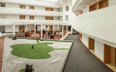 Bright interior courtyard with open atrium, landscaped central garden and comfortable lounge seating at NH Collection Mexico City Airport T2.