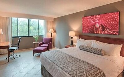 Spacious guest room with king bed, work desk, lounge chair and modern décor at Crowne Plaza Panama.