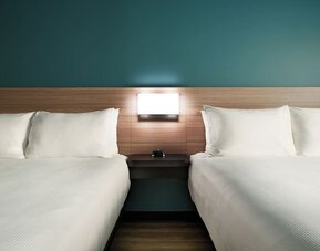 Guest room with two queen beds, modern headboards and comfortable bedding at Hyatt Select Philadelphia Airport.