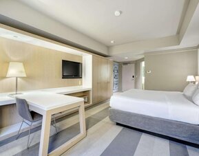 Bright guest room featuring a king bed, large work desk, flat-screen TV and modern furnishings at Royal Sonesta Minneapolis.