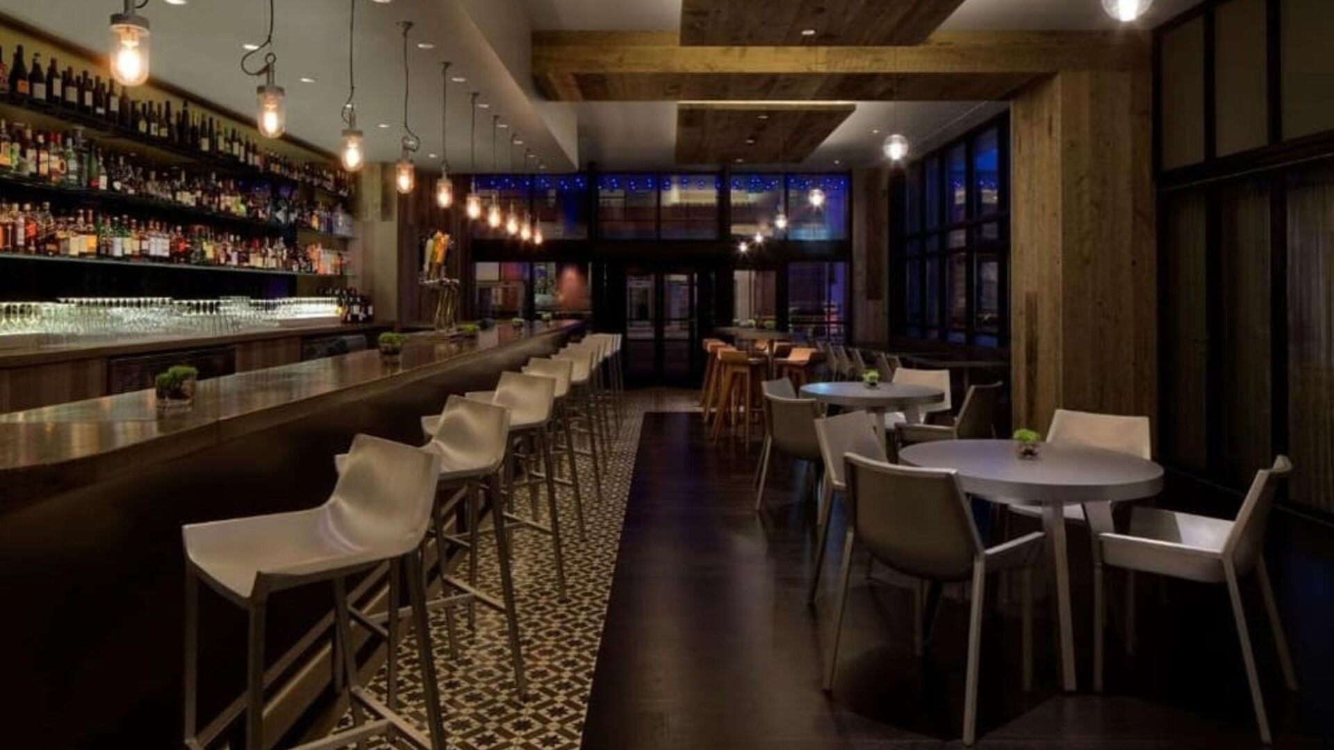 Contemporary hotel bar with a long counter, comfortable seating and ambient lighting at Royal Sonesta Minneapolis.