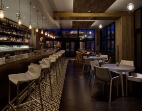 Contemporary hotel bar with a long counter, comfortable seating and ambient lighting at Royal Sonesta Minneapolis.