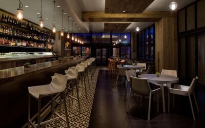 Contemporary hotel bar with a long counter, comfortable seating and ambient lighting at Royal Sonesta Minneapolis.