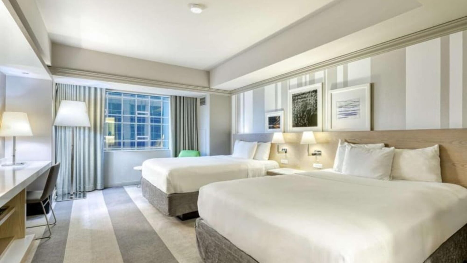 Spacious guest room with two queen beds, modern furnishings and large window at Royal Sonesta Minneapolis.