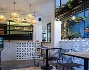 Stylish dining area at 103 Wonderful House featuring colorful tropical wall art, pendant lighting and café-style seating.
