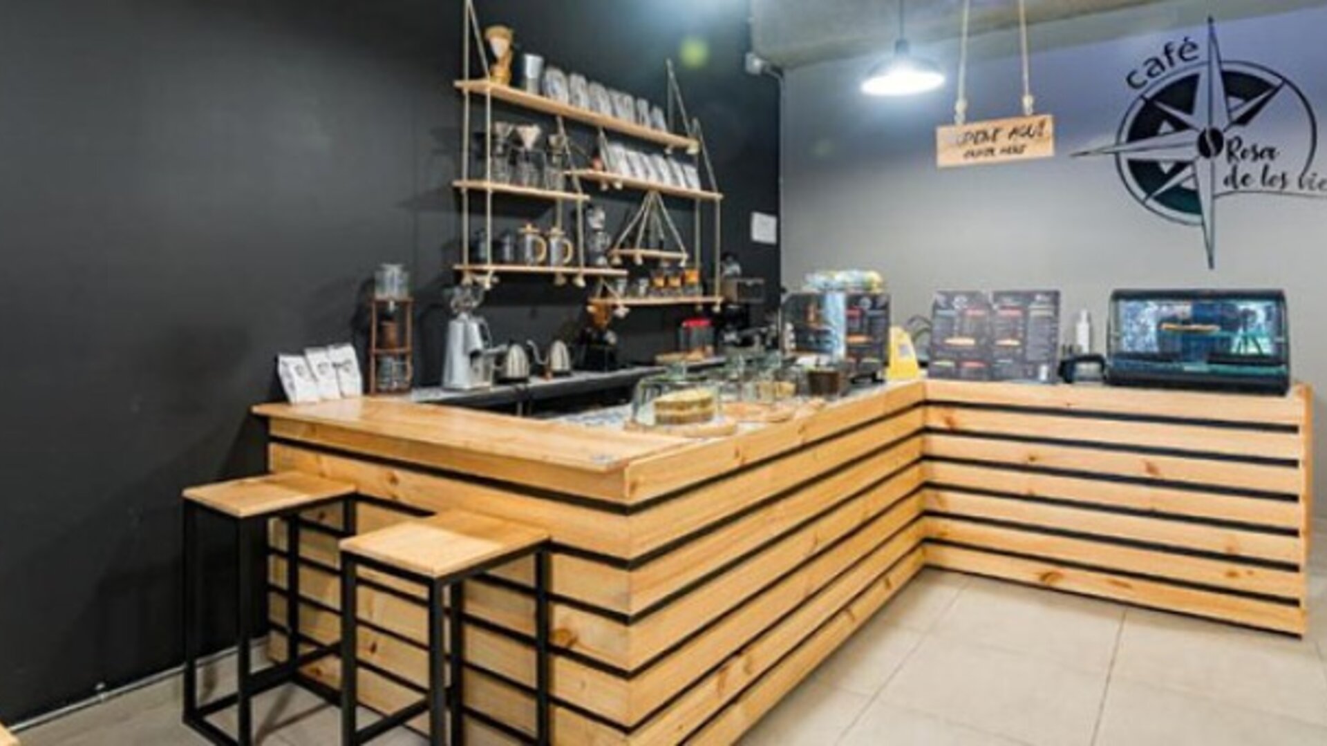 Café counter at Hotel Loft 32 featuring wooden finishes, bar stools and beverage service equipment.