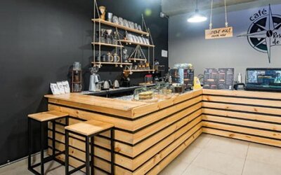 Café counter at Hotel Loft 32 featuring wooden finishes, bar stools and beverage service equipment.