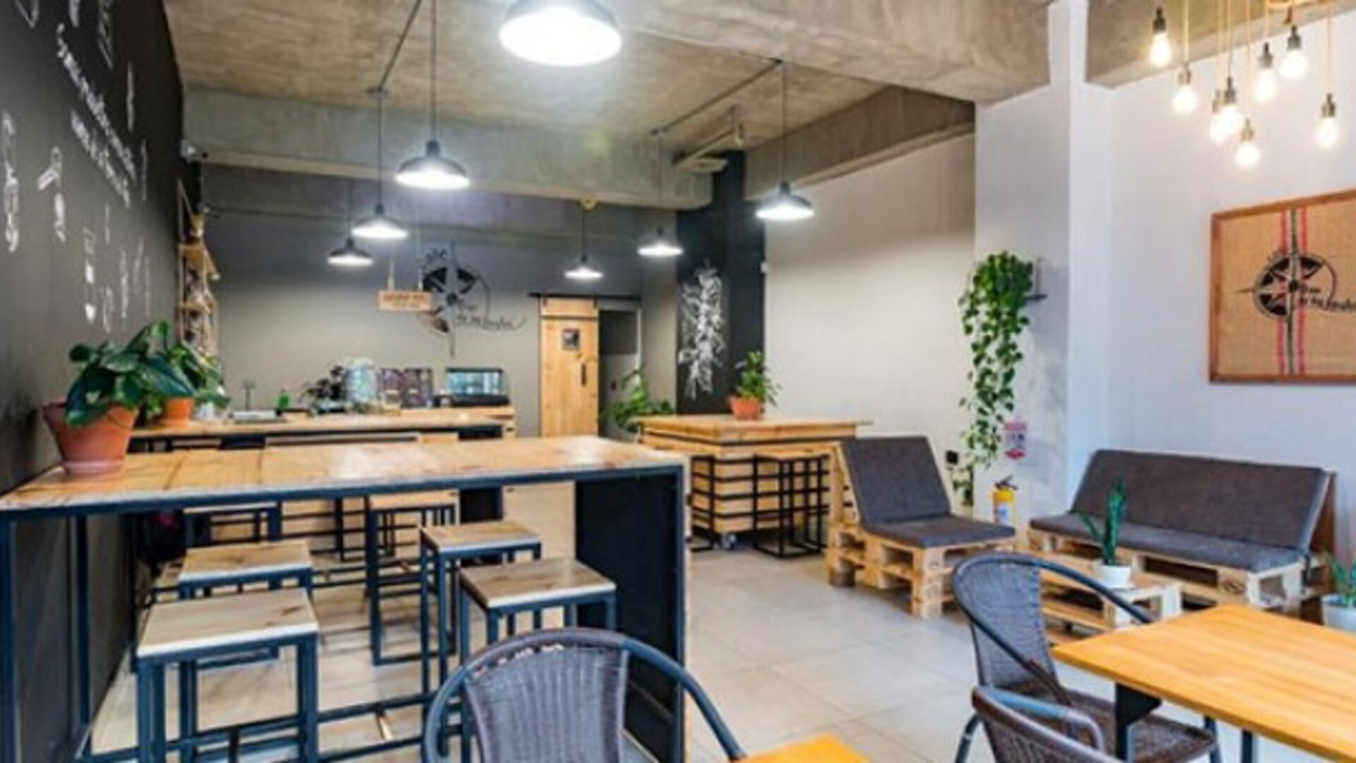 Dining and lounge area at Hotel Loft 32 featuring wooden tables, casual seating, pendant lights and contemporary industrial décor.