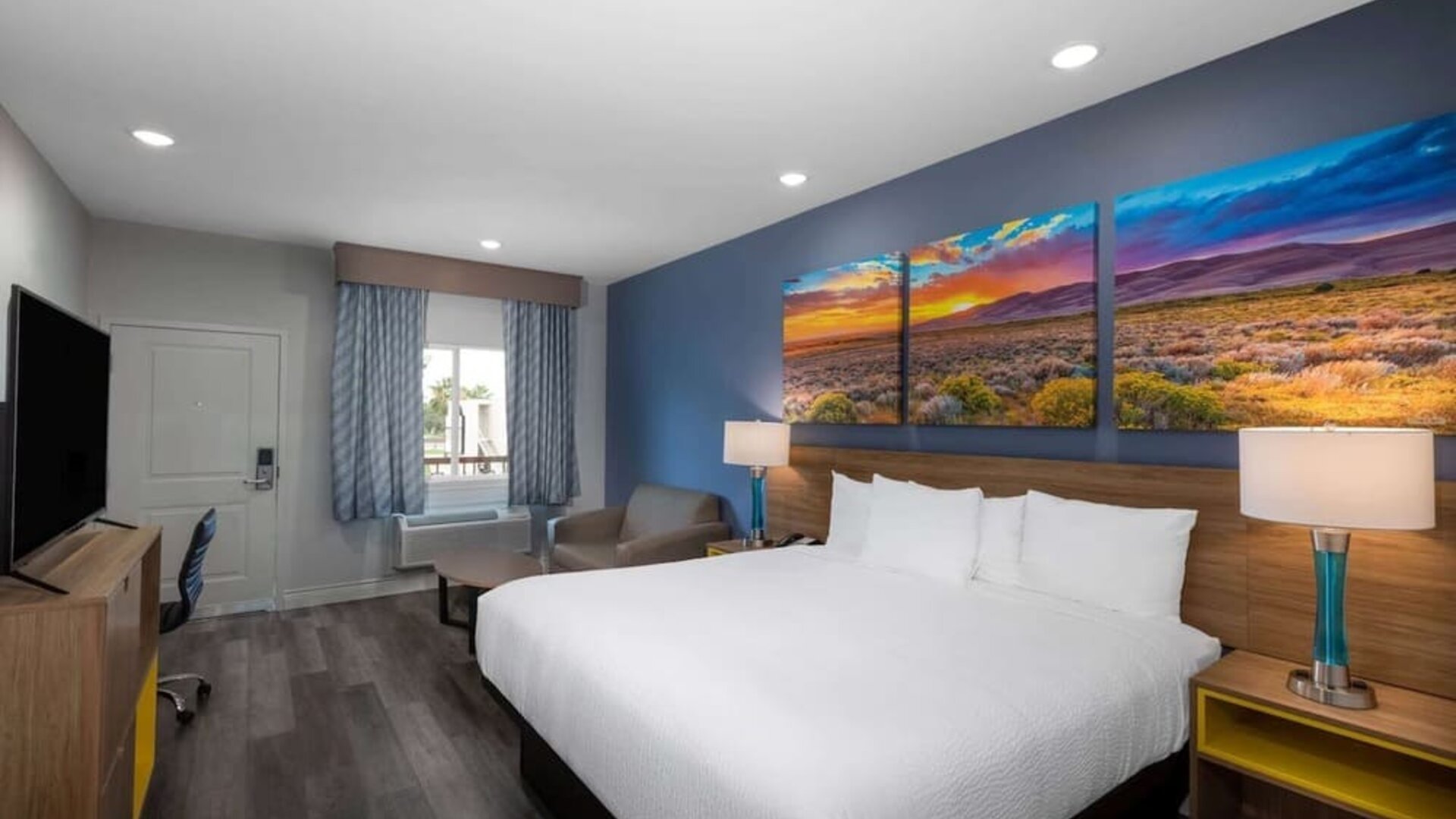 Spacious king room at Days Inn & Suites By Wyndham Downtown/University Of Houston featuring a king bed, seating area, work desk and flat-screen TV.
