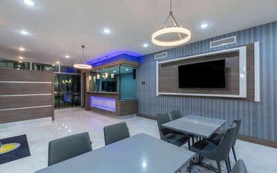 Lobby area at Days Inn & Suites By Wyndham Downtown/University Of Houston featuring dining tables, modern lighting and a wall-mounted TV.