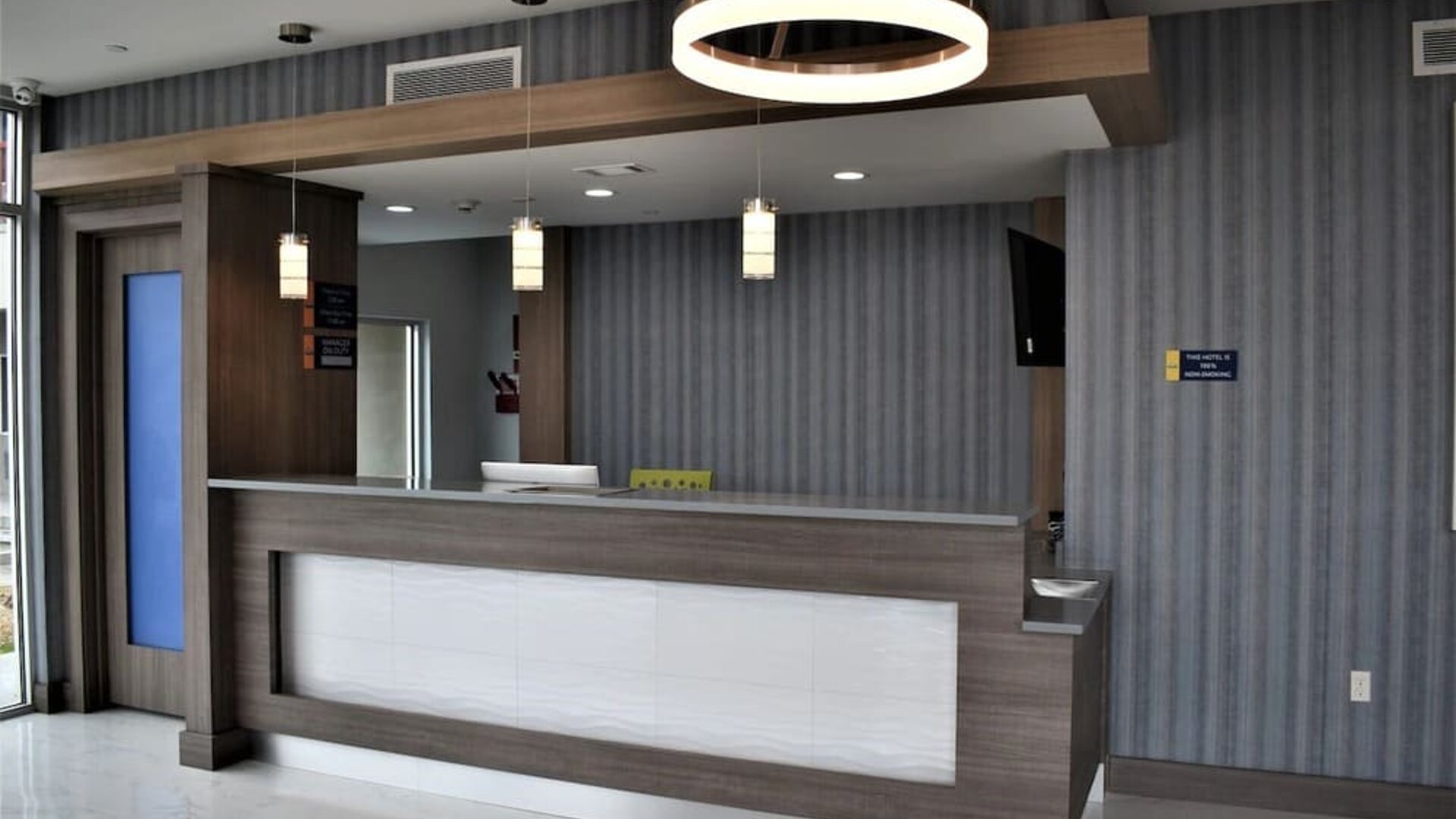 Reception desk at Days Inn & Suites By Wyndham Downtown/University Of Houston featuring contemporary wood finishes and pendant lighting.