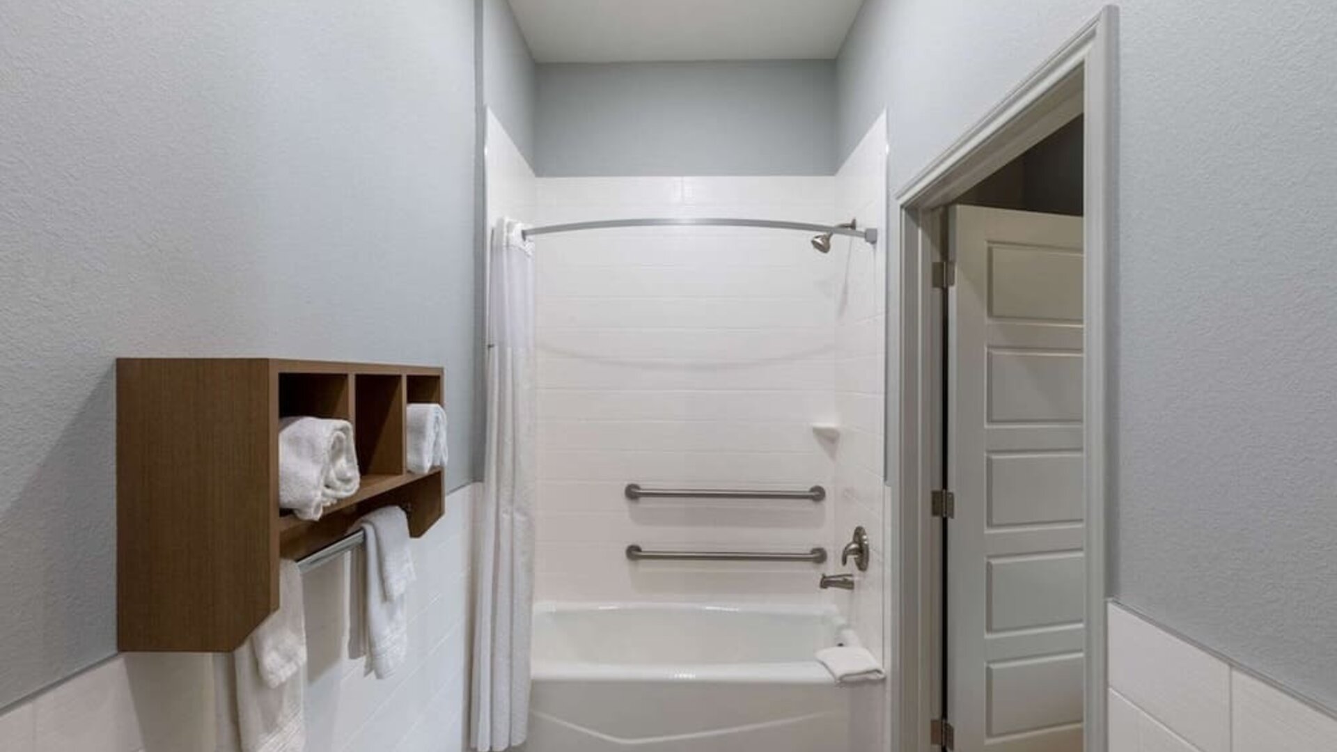 Guest bathroom at Days Inn & Suites By Wyndham Downtown/University Of Houston featuring a shower-tub combination, grab bars and towel storage.