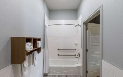 Guest bathroom at Days Inn & Suites By Wyndham Downtown/University Of Houston featuring a shower-tub combination, grab bars and towel storage.