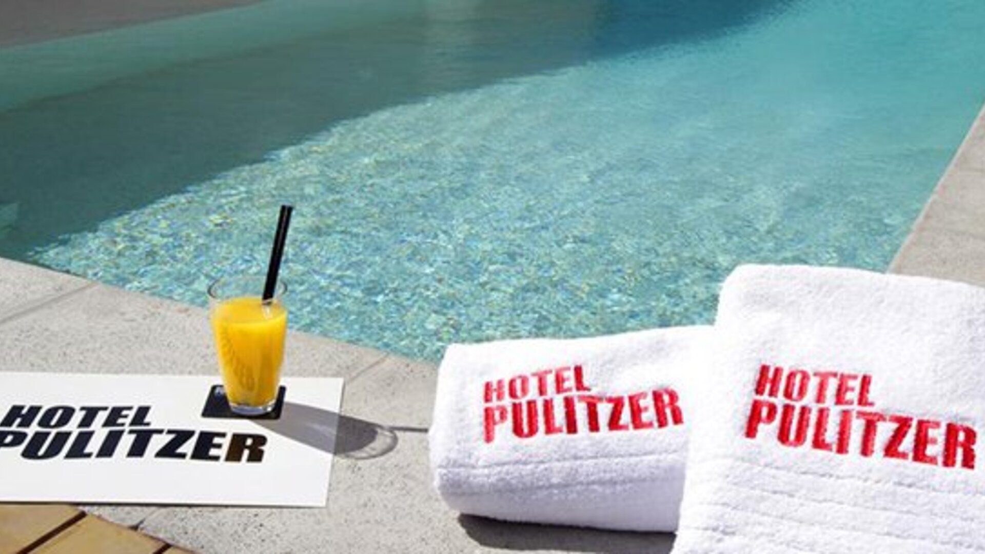 Swimming pool at Hotel Pulitzer Buenos Aires featuring poolside towels and a refreshing drink.