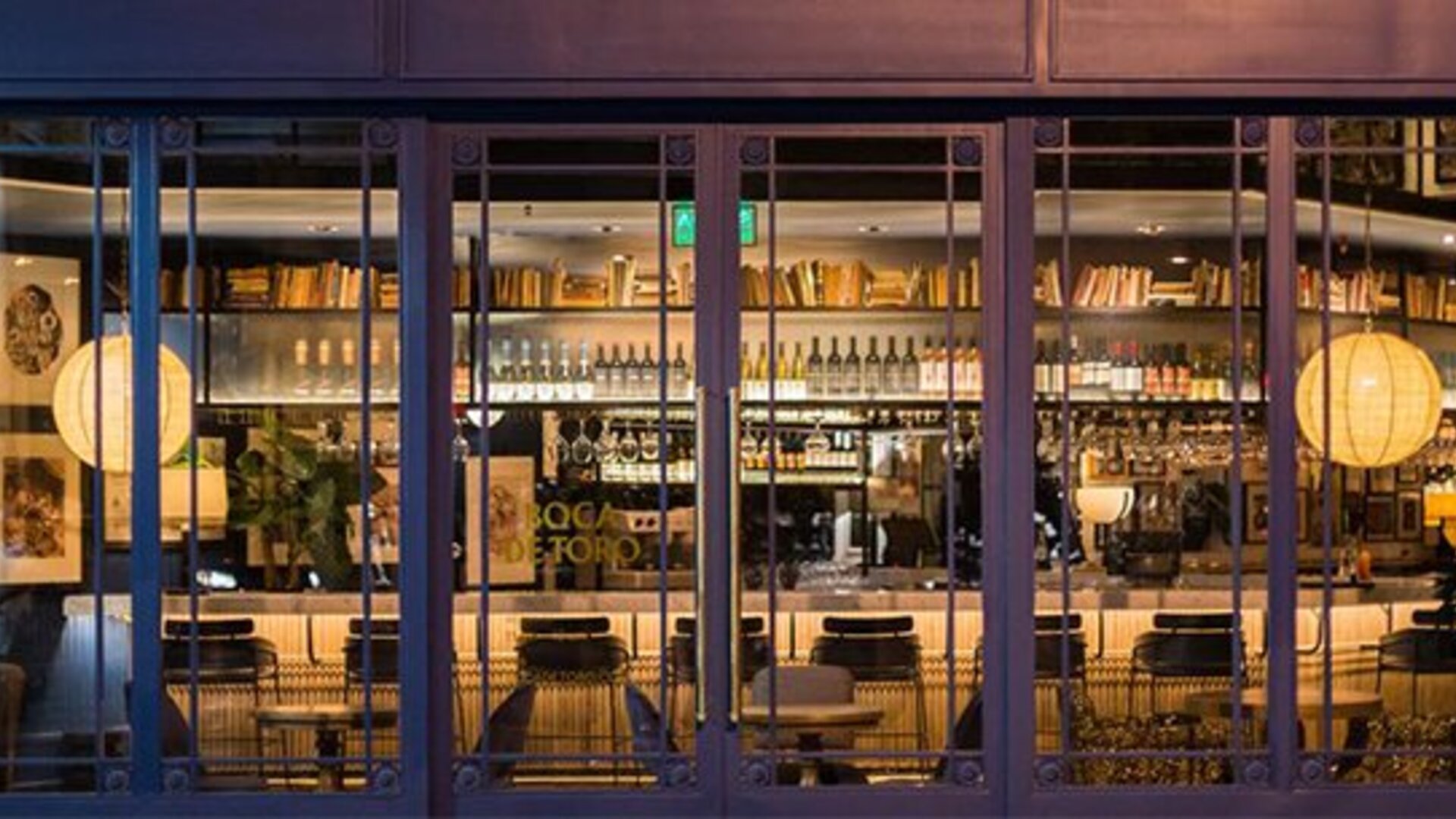Hotel bar at Hotel Pulitzer Buenos Aires featuring a well-stocked bar, counter seating and warm ambient lighting.