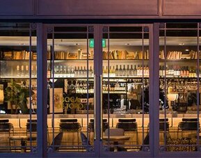 Hotel bar at Hotel Pulitzer Buenos Aires featuring a well-stocked bar, counter seating and warm ambient lighting.