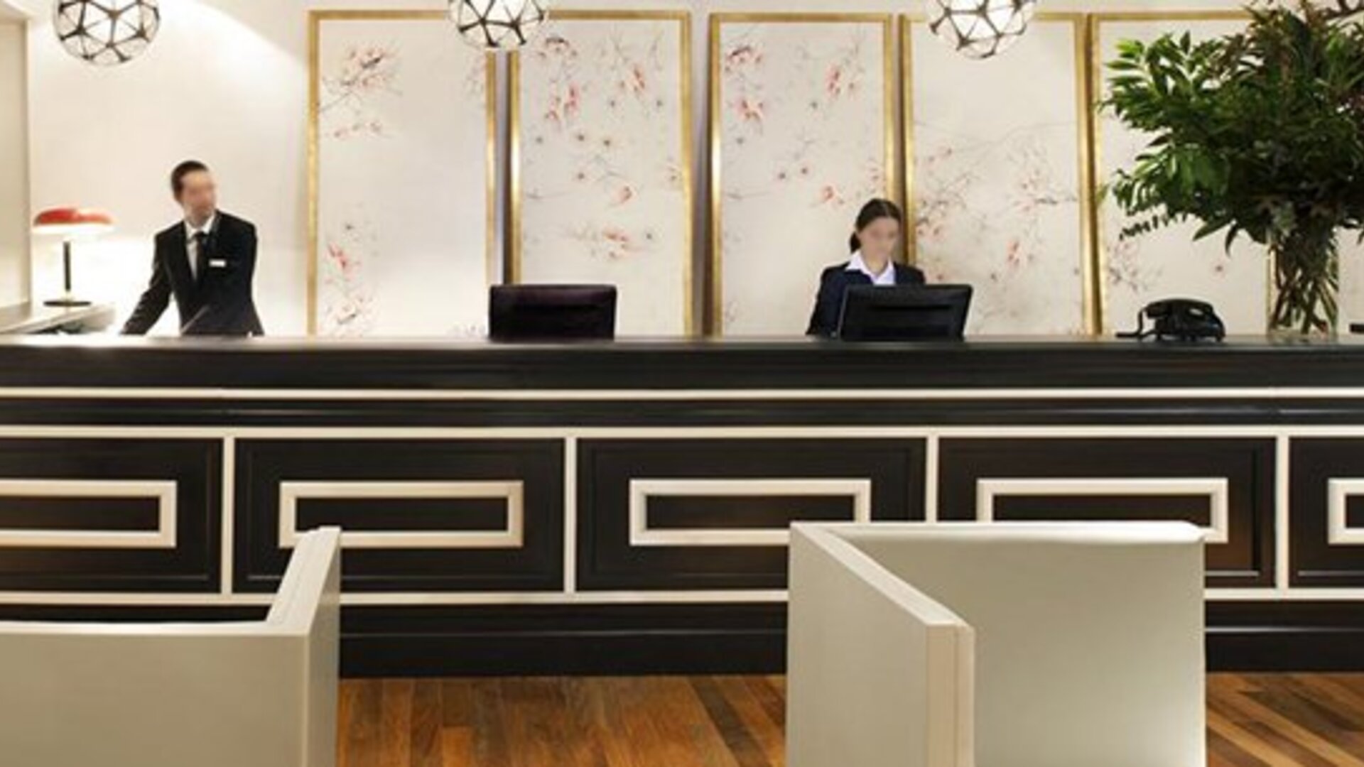 Reception desk at Hotel Pulitzer Buenos Aires featuring a sophisticated black-and-white counter, decorative wall panels and hotel staff.