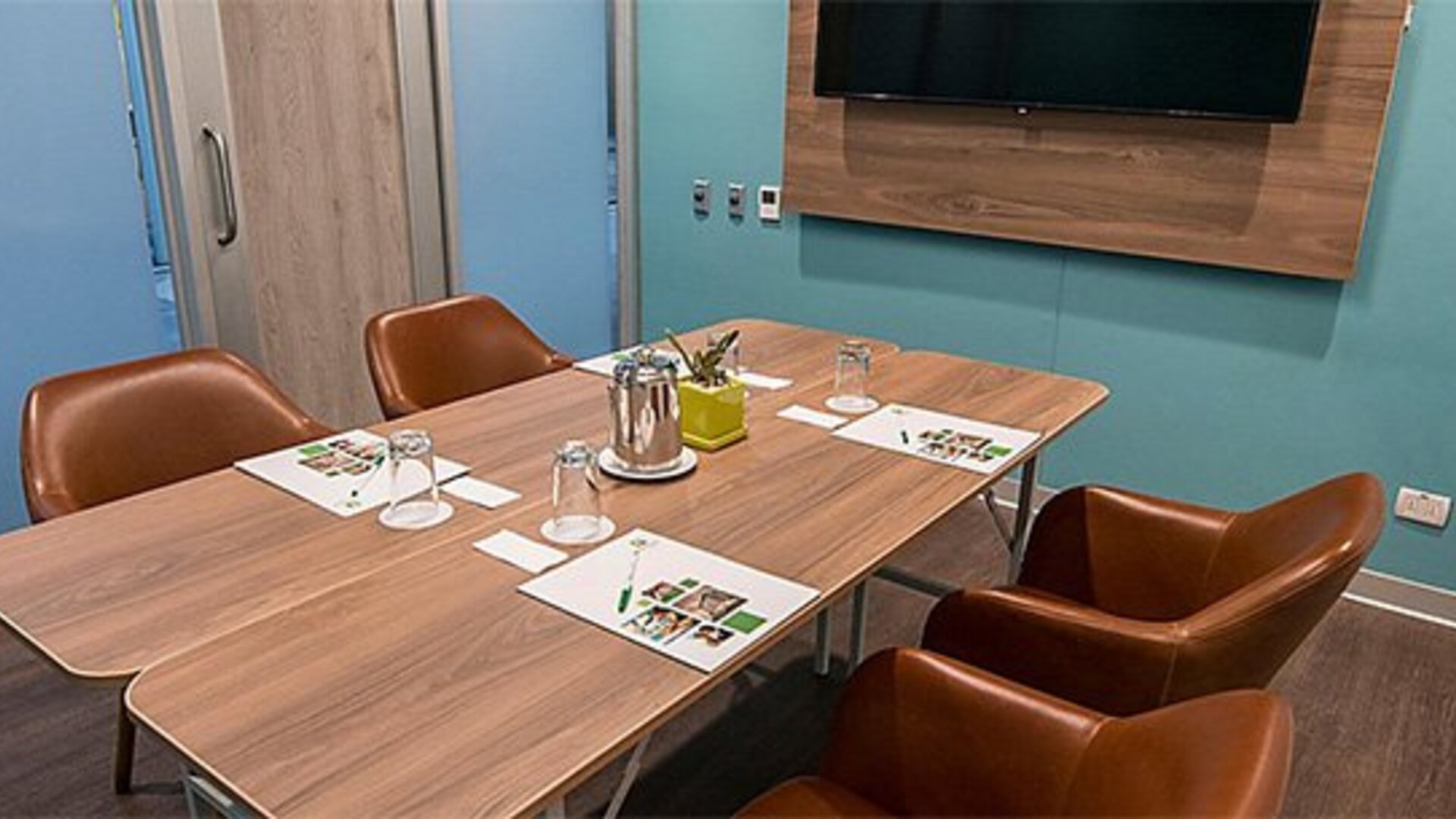 Meeting room at Holiday Inn Lima Airport featuring a conference table, leather chairs, presentation materials and a wall-mounted screen.