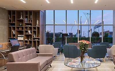 Lobby area at Holiday Inn Lima Airport featuring contemporary sofas, armchairs, bookshelves and floor-to-ceiling windows.