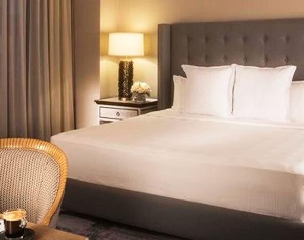 Spacious guest room at Hotel Marquis Reforma featuring a king bed, bedside lamps and a dining area.